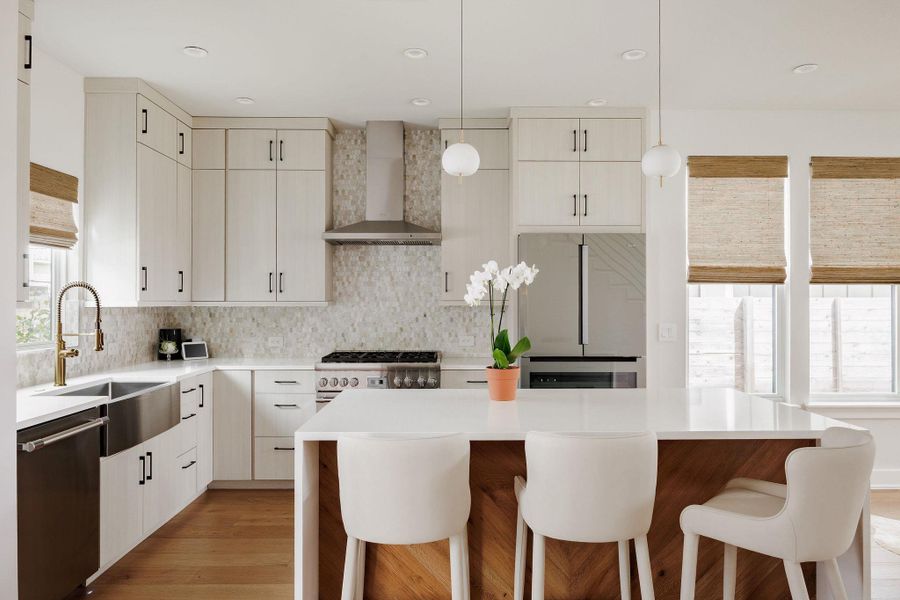 Kitchen featuring decorative light fixtures, backsplash, and light stone countertops