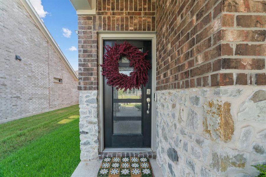 Doorway to property with brick siding, stone siding, and a lawn Doorway to property with brick siding, stone siding, and a lawn