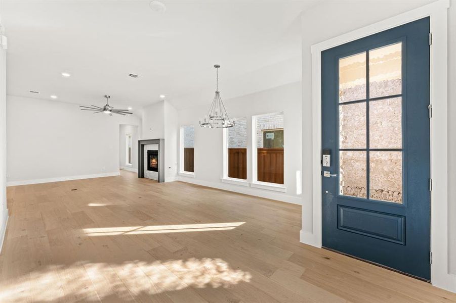 Unfurnished living room with light hardwood / wood-style floors and ceiling fan with notable chandelier