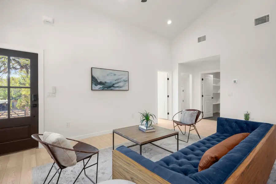 Living area featuring high vaulted ceiling, light wood-style floors, and recessed lighting