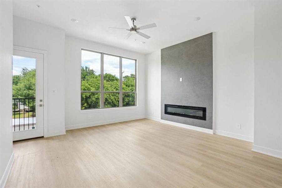 Unfurnished living room featuring light wood-style flooring, baseboards, a fireplace, and ceiling fan