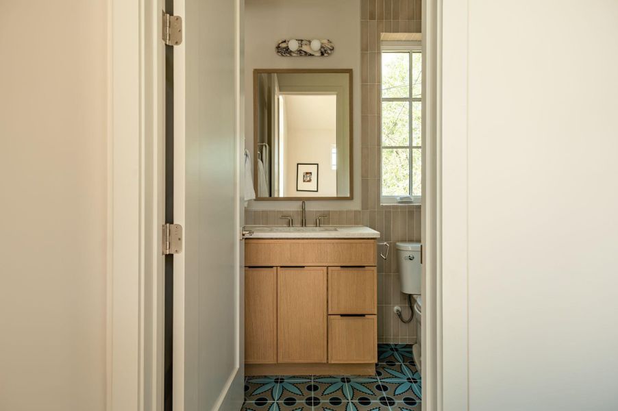A modern vanity anchors this stylish bathroom featuring vibrant patterned floor tile. A modern vanity anchors this stylish bathroom featuring vibrant patterned floor tile.