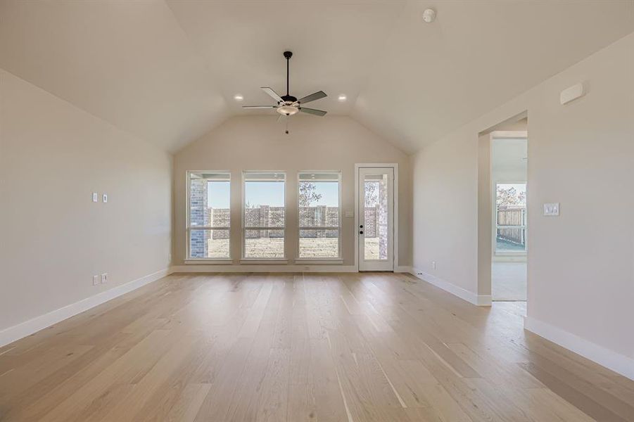 Unfurnished living room with healthy amount of natural light, light wood-type flooring, lofted ceiling, a ceiling fan, and recessed lighting