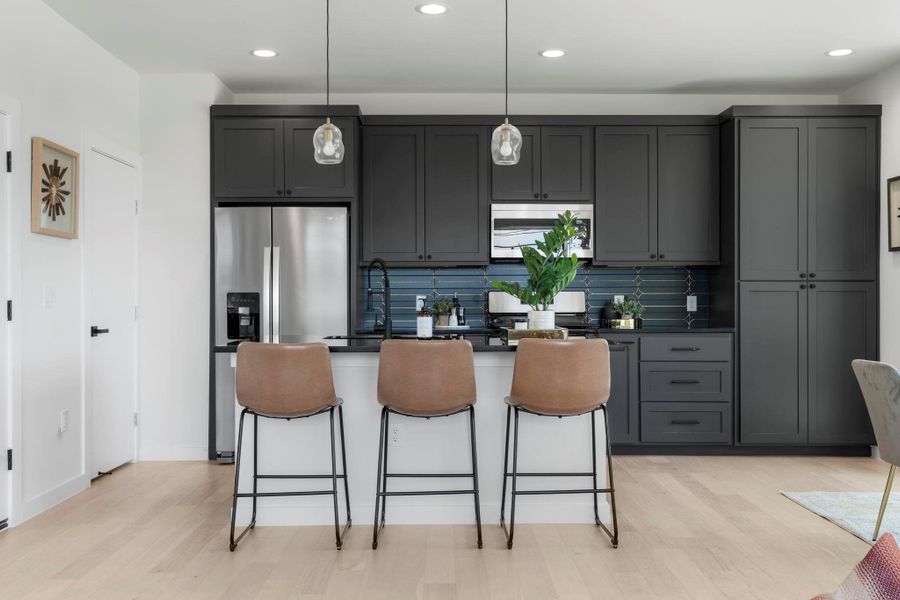 Kitchen with tasteful backsplash, decorative light fixtures, recessed lighting, appliances with stainless steel finishes, and light wood-type flooring