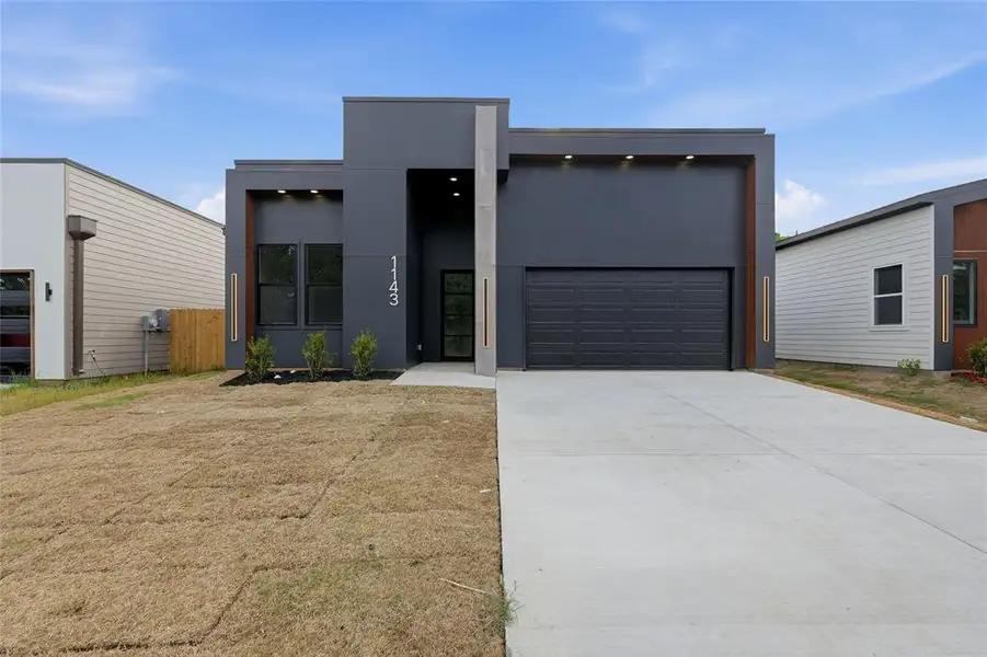 Contemporary gray exterior featuring a prominent garage, a streamlined entryway, and multiple windows Contemporary gray exterior featuring a prominent garage, a streamlined entryway, and multiple windows