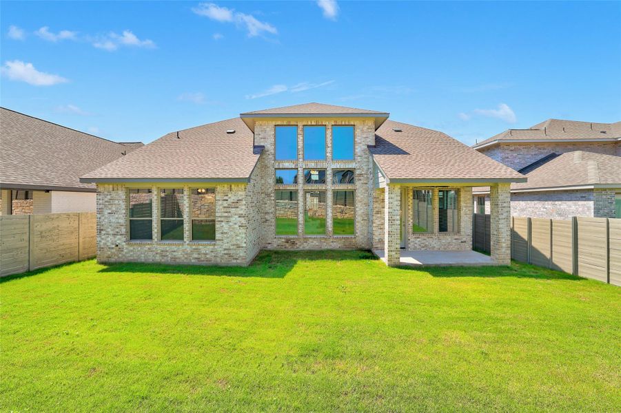 Back of property featuring a shingled roof, brick siding, a fenced backyard, and a patio Back of property featuring a shingled roof, brick siding, a fenced backyard, and a patio
