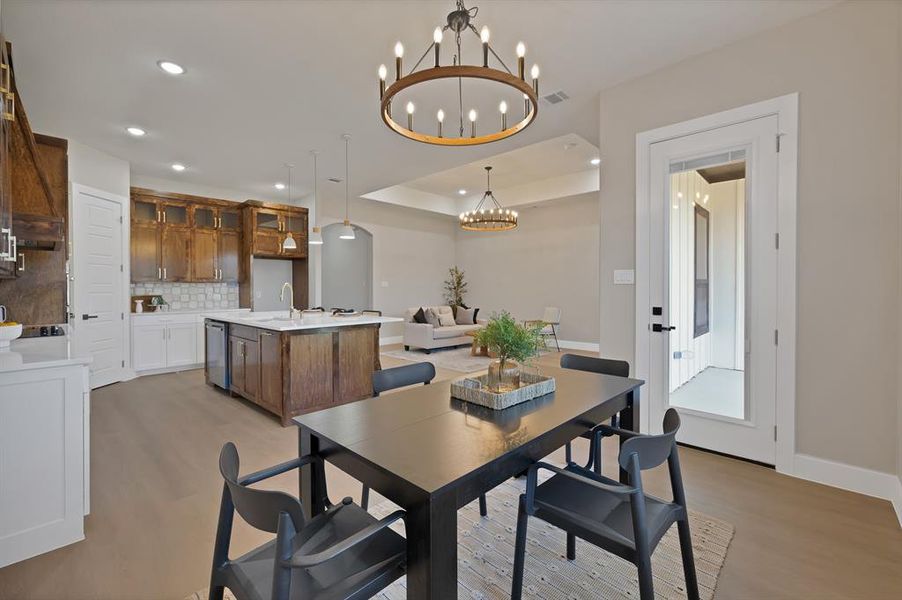 Dining space featuring a chandelier, light wood finished floors, recessed lighting, baseboards, and a tray ceiling