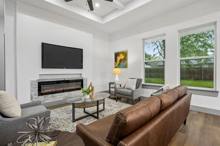 Living room featuring tray ceiling and a stacked stone facade for the electric fireplace.