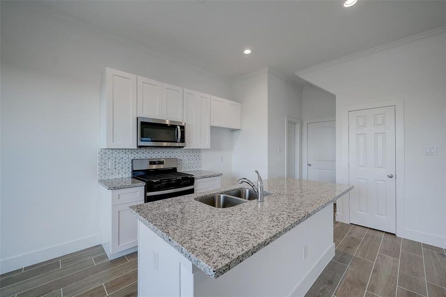 The kitchen sits at the heart of the home between the living and dining areas. Door shown beneath the stairs conceals a sizable pantry, while the door to the left offers a well-sized powder room.