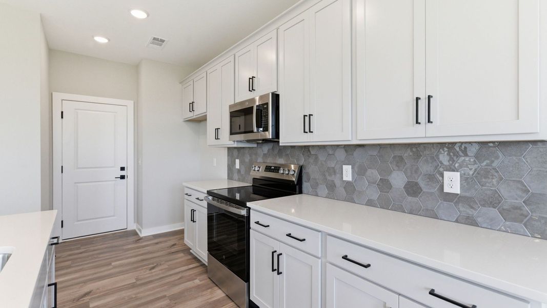 Kitchen with tile backsplash, pendant lighting, and quartz countertops