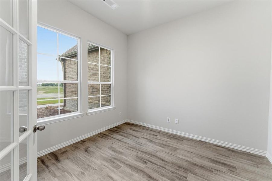 Room featuring French doors with glass inserts, wood-finish flooring, and white baseboards