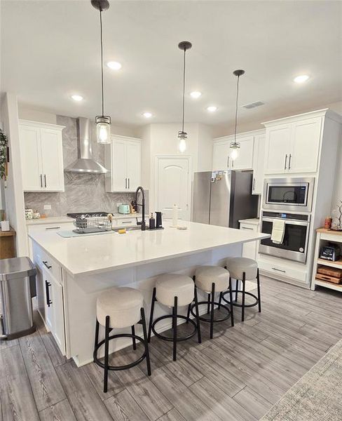 Kitchen with stainless steel appliances, range hood, and oversized island.