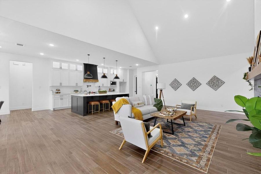 Living room with high vaulted ceiling, light wood-style floors, and recessed lighting Living room with high vaulted ceiling, light wood-style floors, and recessed lighting