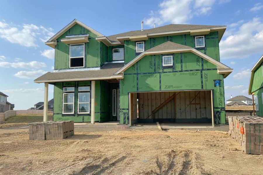Property in mid-construction with a porch, driveway, and a garage