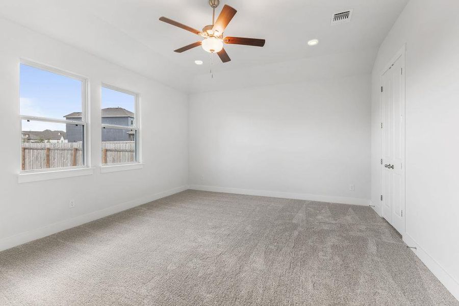 A spacious, naturally illuminated room features plush carpeting and a modern ceiling fan for ultimate comfort. A spacious, naturally illuminated room features plush carpeting and a modern ceiling fan for ultimate comfort.