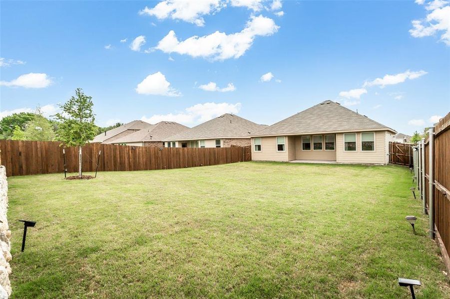 The property features an extensive backyard with a well-maintained lawn and a privacy fence