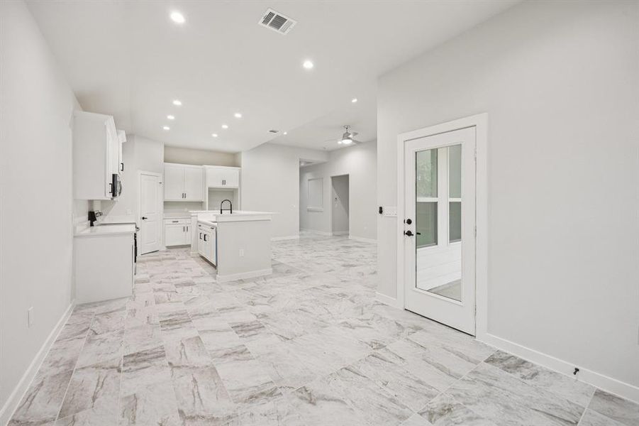 Kitchen featuring recessed lighting, an island with sink, white cabinets, a ceiling fan, and light countertops Kitchen featuring recessed lighting, an island with sink, white cabinets, a ceiling fan, and light countertops