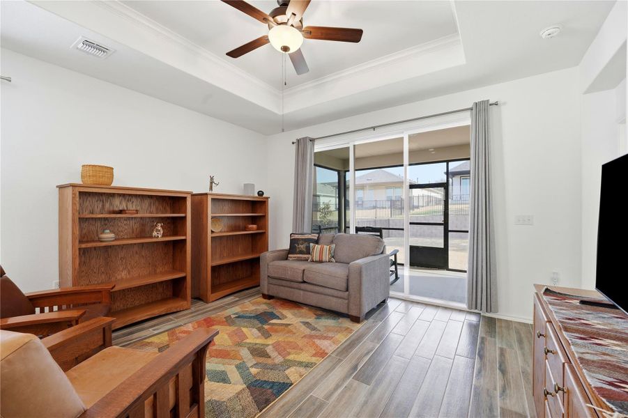 Living area with wood tiled floors, a ceiling fan, crown molding, and a tray ceiling