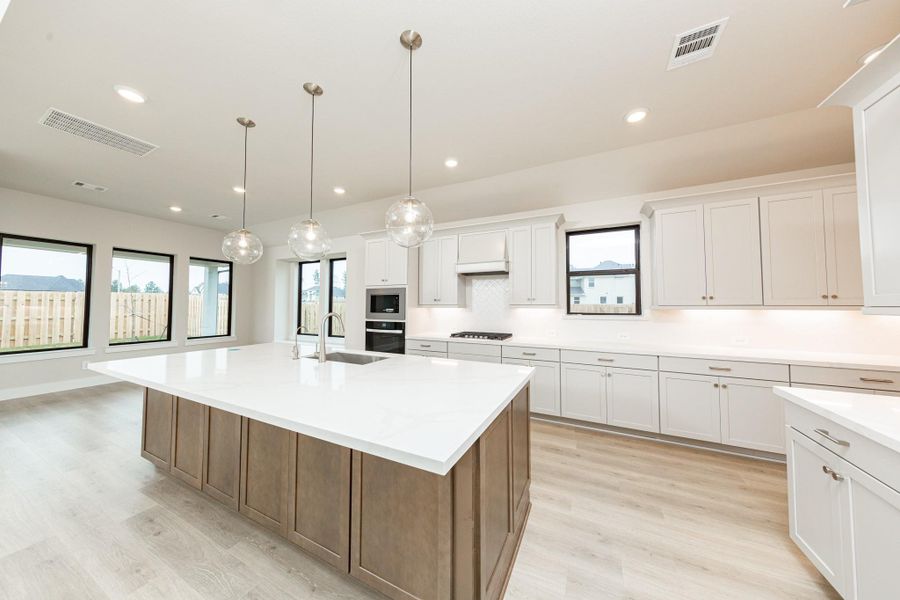 The stunning and generously sized center island features a breakfast bar, perfect for casual dining and entertaining. The island is beautifully designed with pristine quartz countertop and elegant pendant lights.