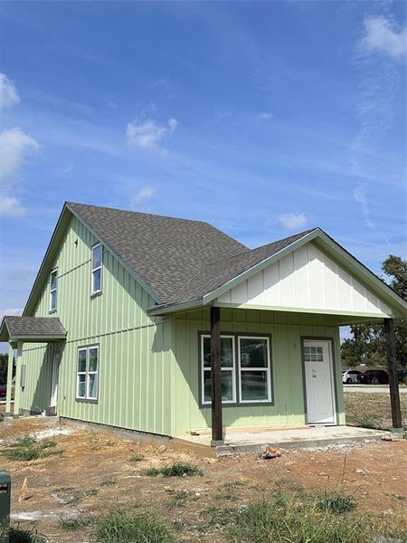 View of front of home featuring a shingled roof, covered porch, and board and batten siding