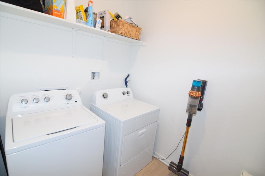 A dedicated laundry space features crisp white walls and convenient overhead storage shelving.