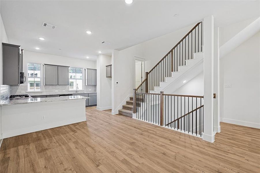 Kitchen featuring gray cabinetry, light wood-style flooring, tasteful backsplash, recessed lighting, and a peninsula