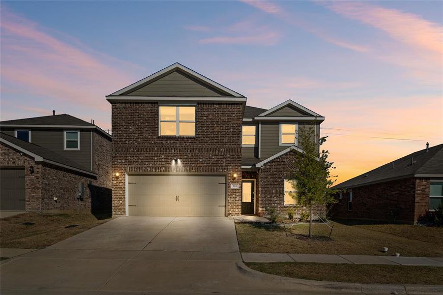 Traditional home with driveway, brick siding, and an attached garage