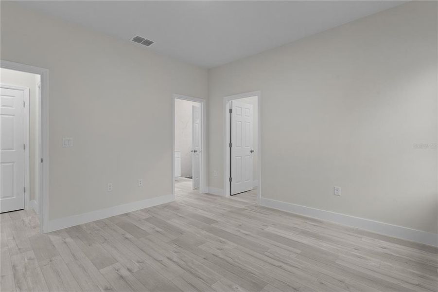 Primary bedroom with entry at far left, ensuite bathroom entry in middle, and walk-in closet to the right.