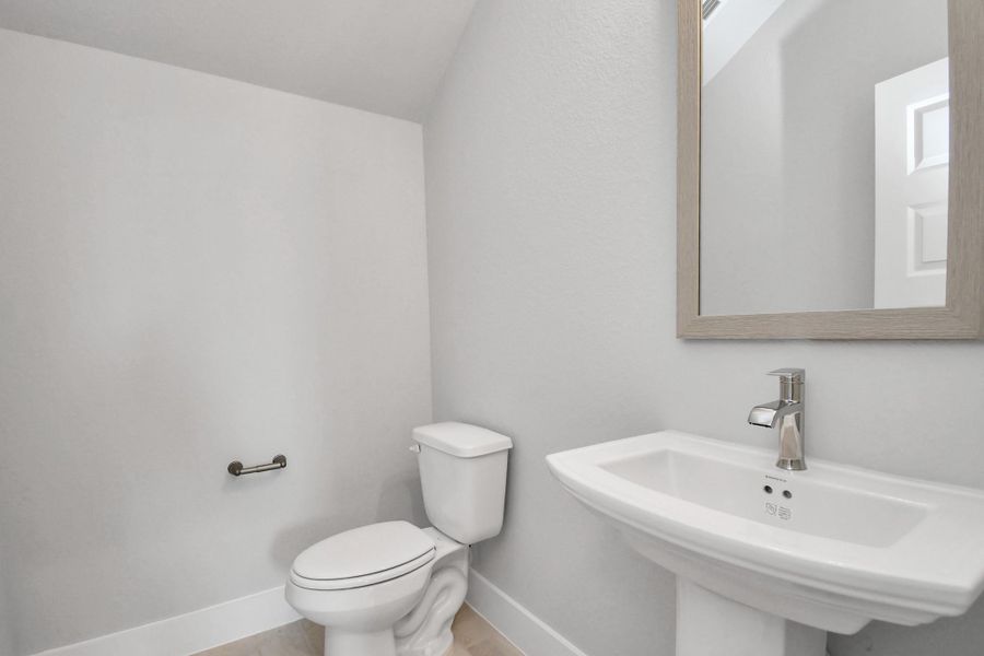This half bathroom features a stylish pedestal sink, modern hardware, and bright recessed lighting, creating a sleek and inviting space. Sample photo of completed home with similar floor plan. Actual colors and selections may vary.