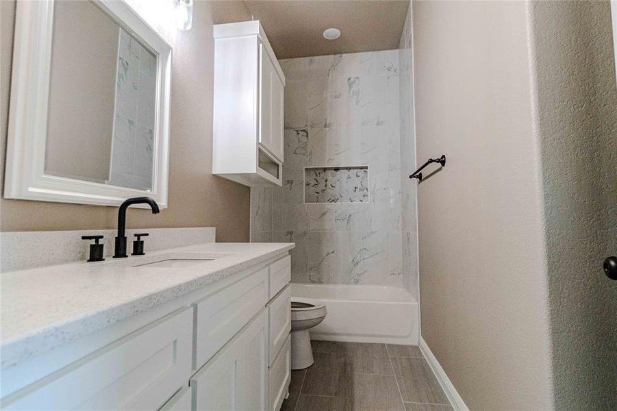 Full bathroom with tiled shower / bath, vanity, and toilet