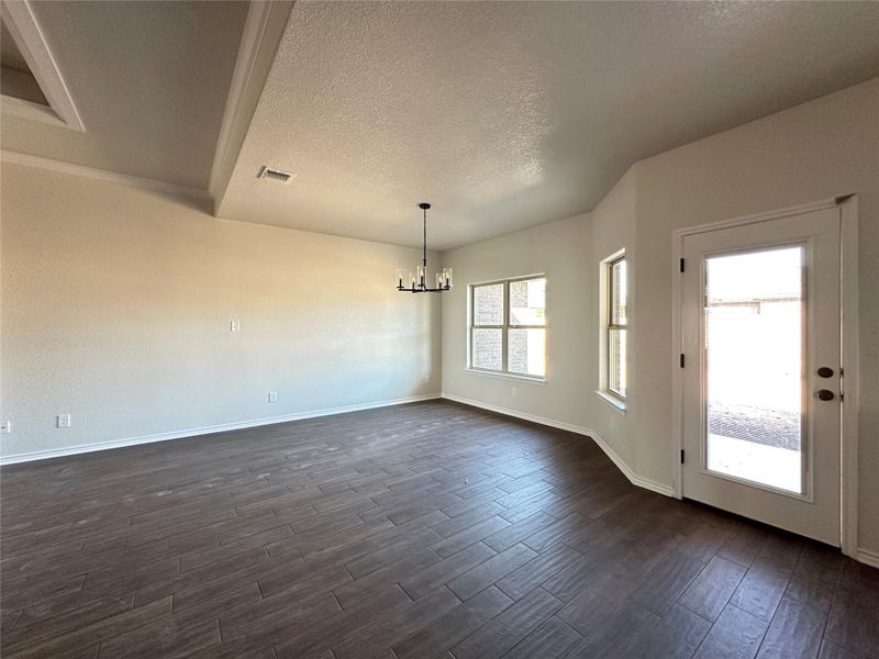 Spare room with dark wood-style floors, a textured ceiling, and a chandelier