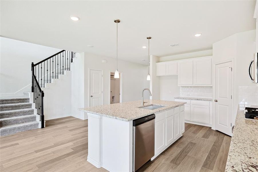 Kitchen featuring appliances with stainless steel finishes, white cabinets, light wood-type flooring, and tasteful backsplash