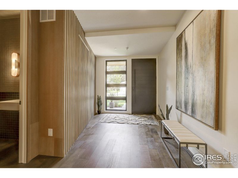 Foyer with custom door, windows and white oak slated wood wall