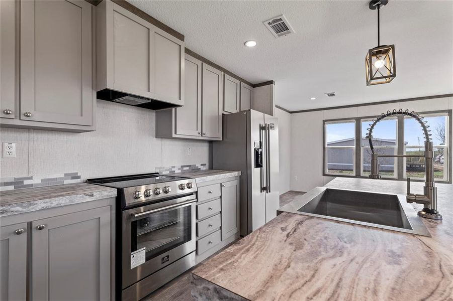 Kitchen with gray cabinetry, stainless steel appliances, hanging light fixtures, crown molding, and a textured ceiling