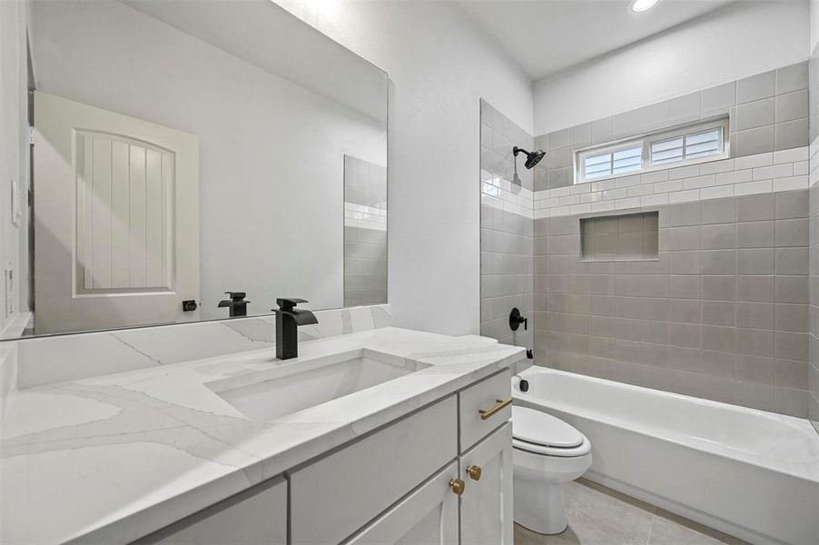 Full bathroom with tile patterned flooring, tiled shower / bath combo, vanity, and toilet