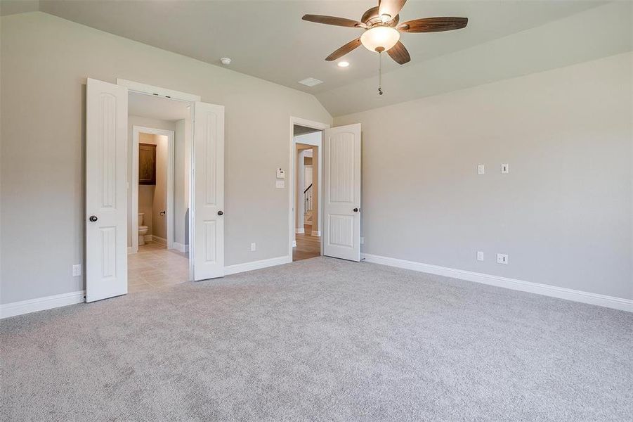 Unfurnished bedroom with ceiling fan, light carpet, and vaulted ceiling