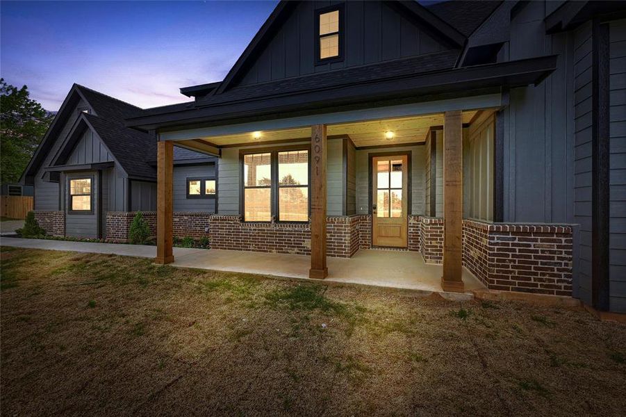 Back of house with roof with shingles, board and batten siding, a porch, and brick siding