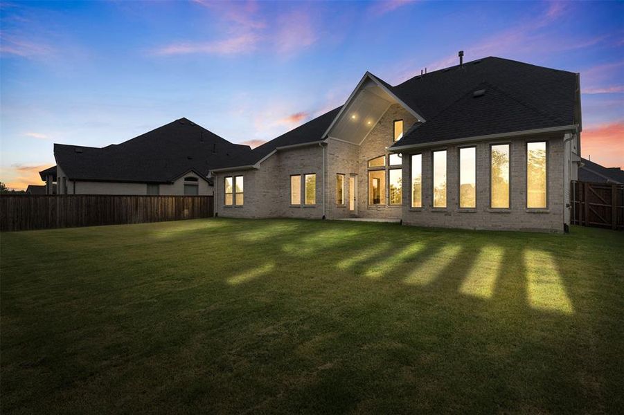 Rear view of house with a fenced backyard, brick siding, and a shingled roof Rear view of house with a fenced backyard, brick siding, and a shingled roof