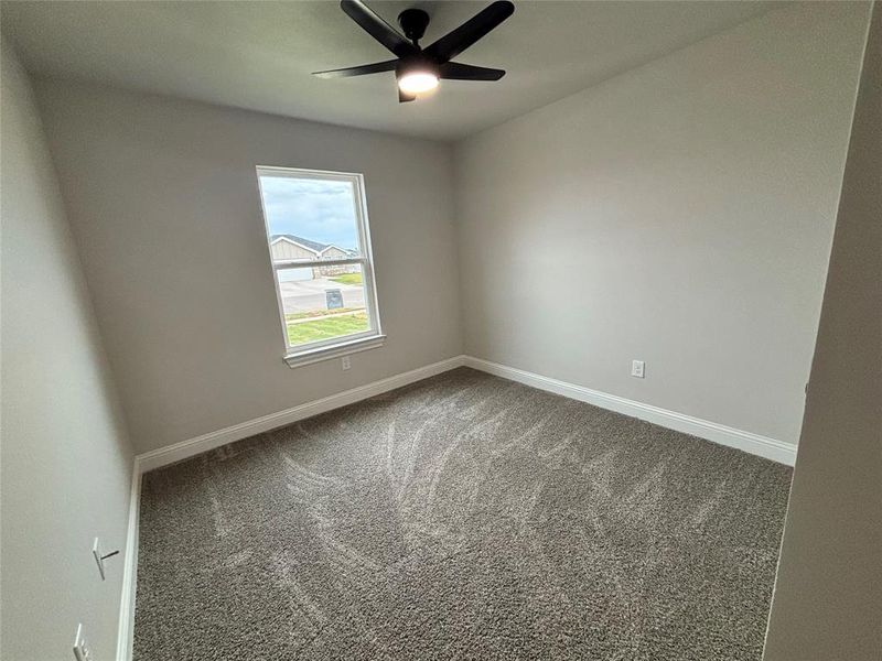 Carpeted empty room with baseboards and a ceiling fan