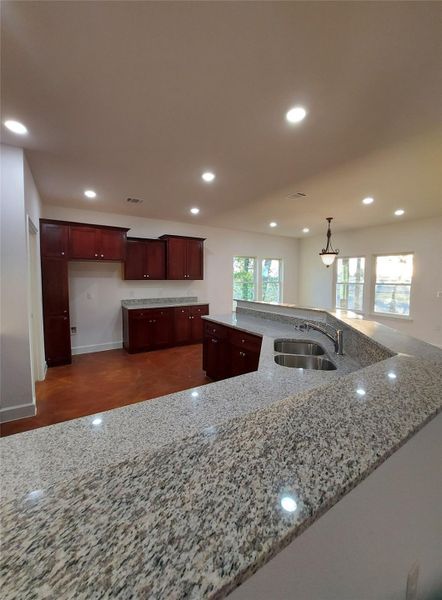 Kitchen featuring light stone counters, decorative light fixtures, and a kitchen island