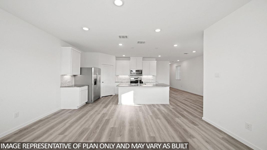 Open-concept kitchen and living area featuring wood-finish flooring, recessed lighting, and white cabinetry
