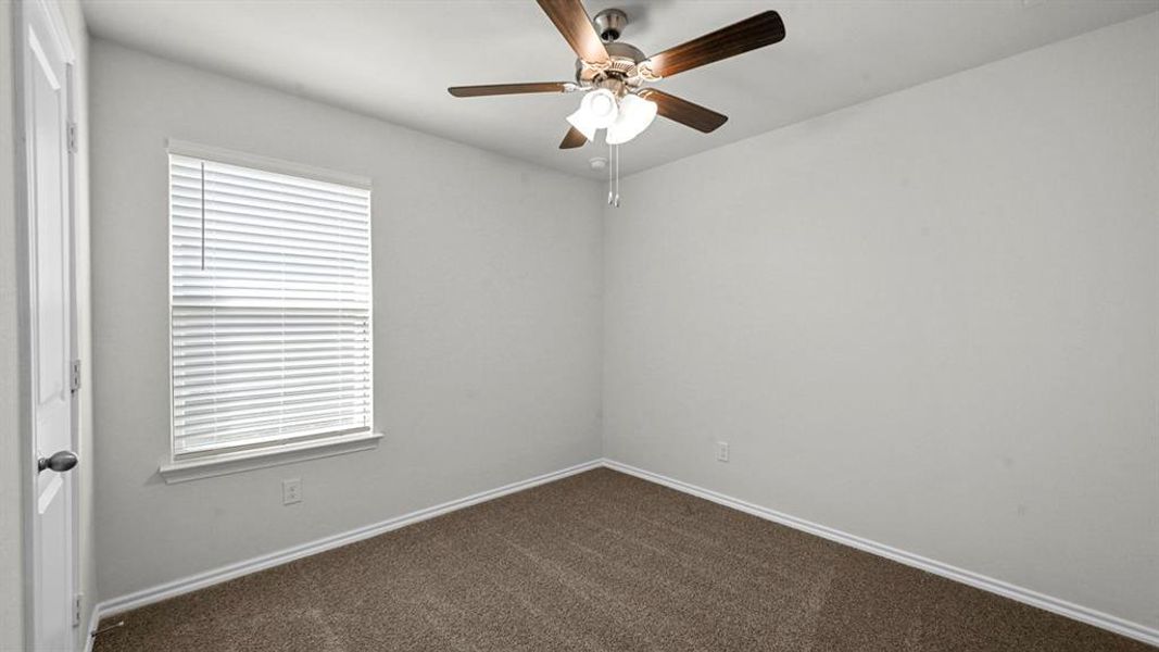 Spare room featuring a ceiling fan and dark colored carpet