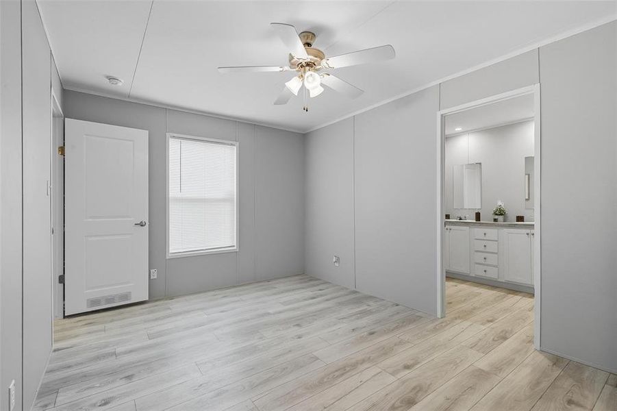 Unfurnished bedroom featuring crown molding, light wood-type flooring, a ceiling fan, and connected bathroom Unfurnished bedroom featuring crown molding, light wood-type flooring, a ceiling fan, and connected bathroom