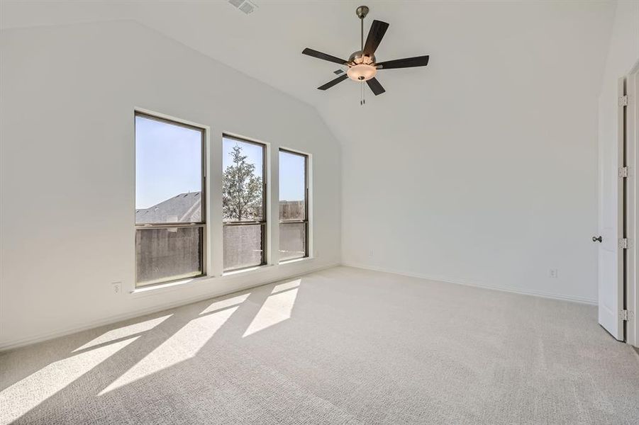 Carpeted spare room featuring ceiling fan and vaulted ceiling