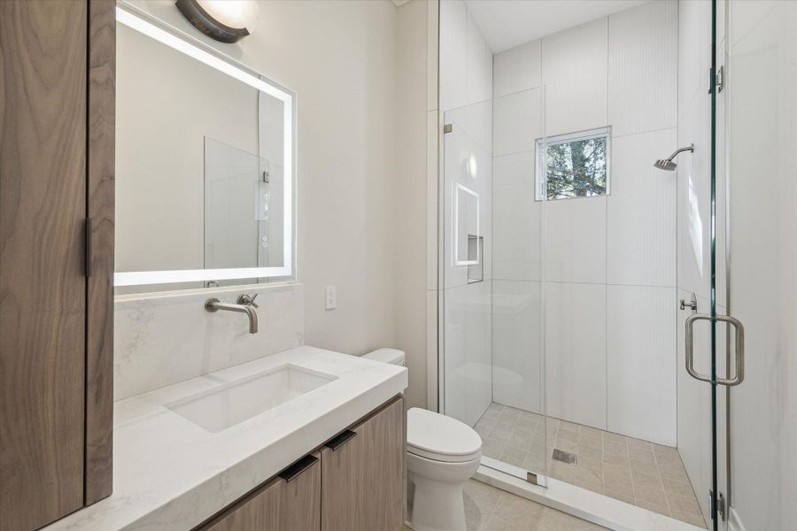 First-floor informal powder and pool bath is conveniently located beside the mud room and just off the backyard. It includes a walk-in shower enclosed in frameless glass for a clean, modern finish.