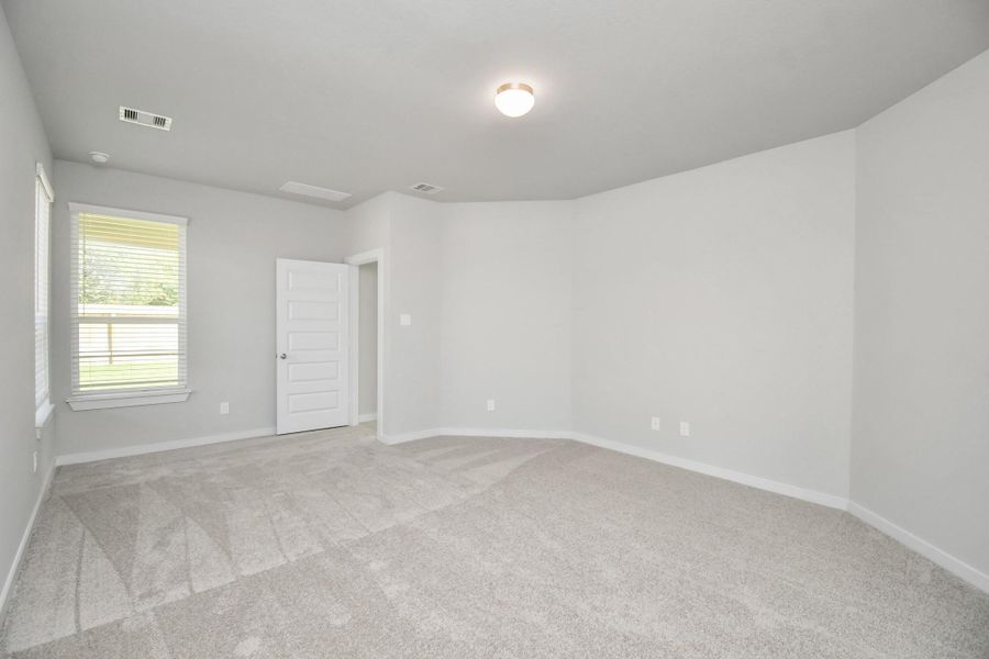 Escape and relax in the exquisite primary suite, a haven to unwind after a long day. The spacious room, boasts plush carpeting, soothing paint tones, high ceilings, and expansive windows adorned with privacy blinds. Sample photo of completed home with similar floor plan. Actual colors and selections may vary.