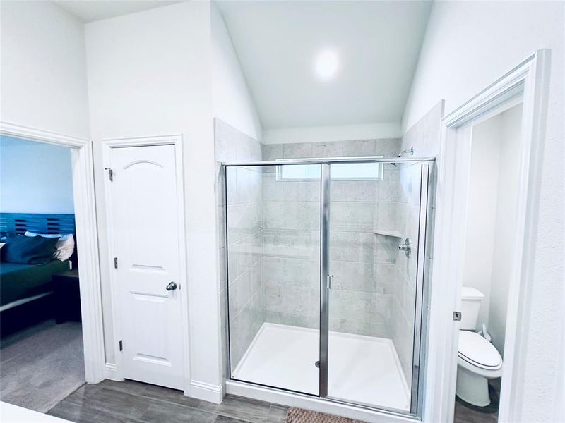 Bathroom with walk in shower, vaulted ceiling, and toilet