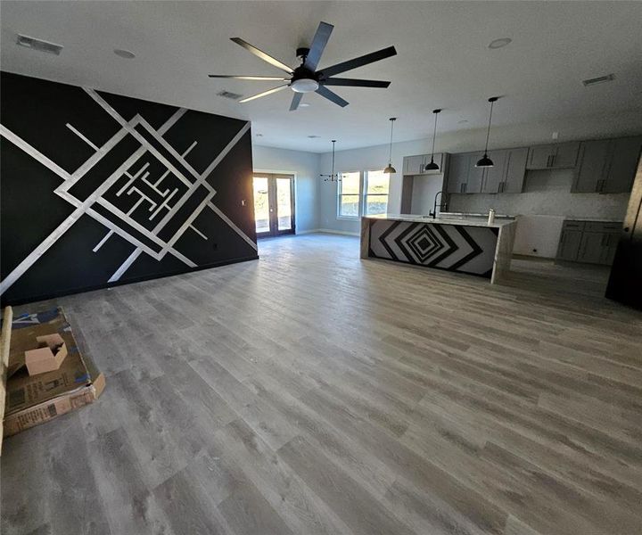 Unfurnished living room with light wood-type flooring, a chandelier, and ceiling fan Unfurnished living room with light wood-type flooring, a chandelier, and ceiling fan
