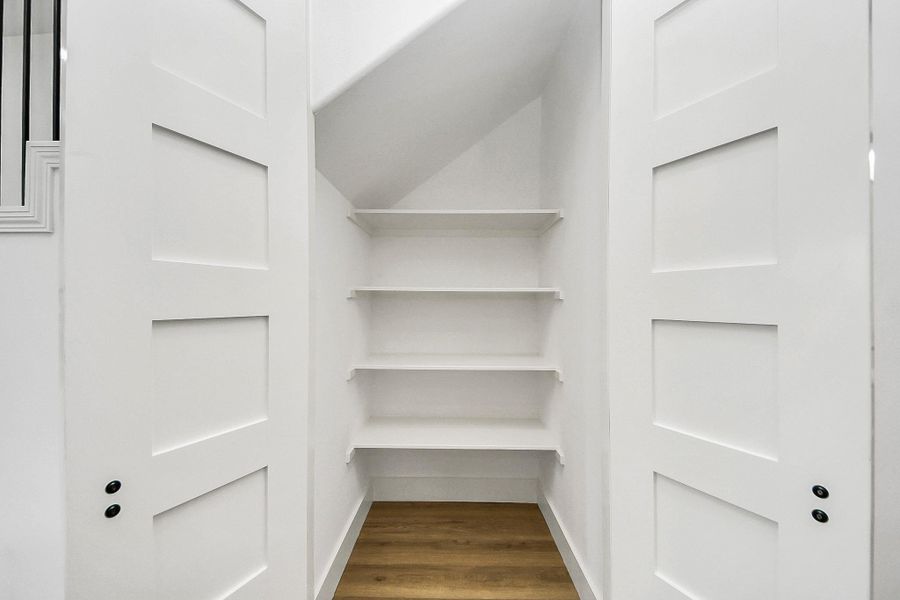Walk-in kitchen pantry with built-in shelving offers ample storage and organization for everyday essentials. Clean, bright design makes it both functional and easy to access.