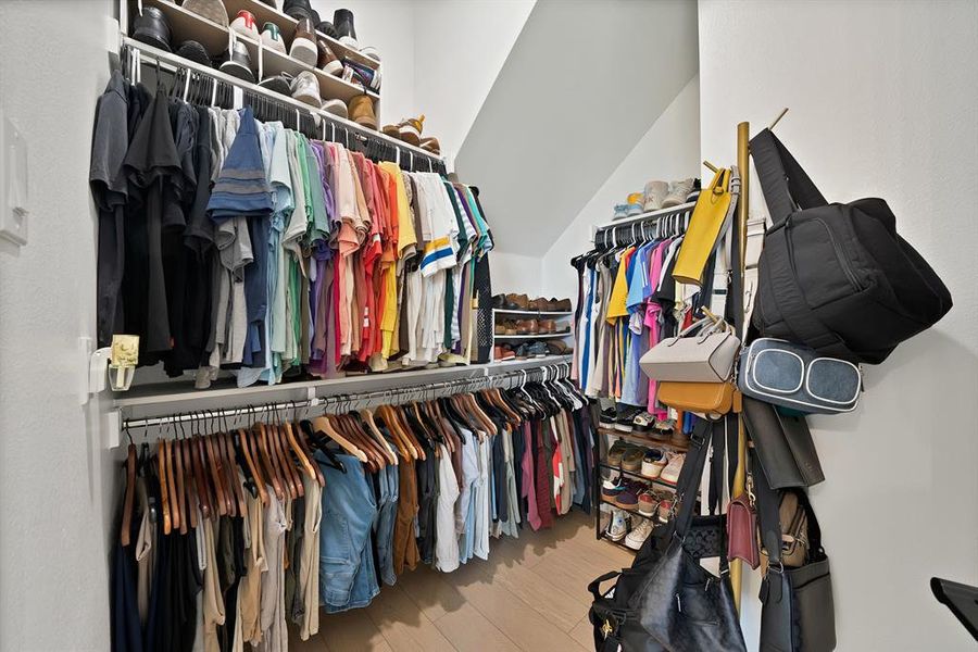 Custom closet system with multiple hanging rods, integrated shelving, and sloped ceiling Custom closet system with multiple hanging rods, integrated shelving, and sloped ceiling